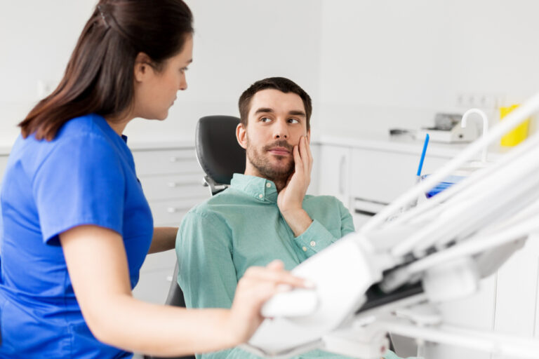 Female dentist talking to male patient complaining of toothache