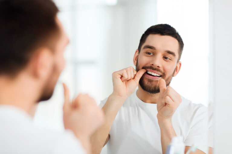 man with dental floss cleaning teeth at bathroom