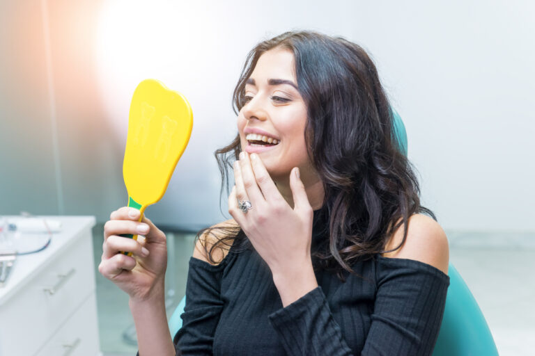 Smiling lady at dentist office looking at her teeth