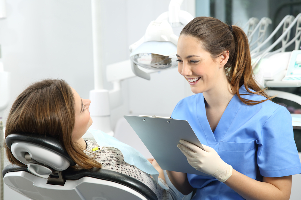 Dentist holding a medical history asking information to a patient before treatment