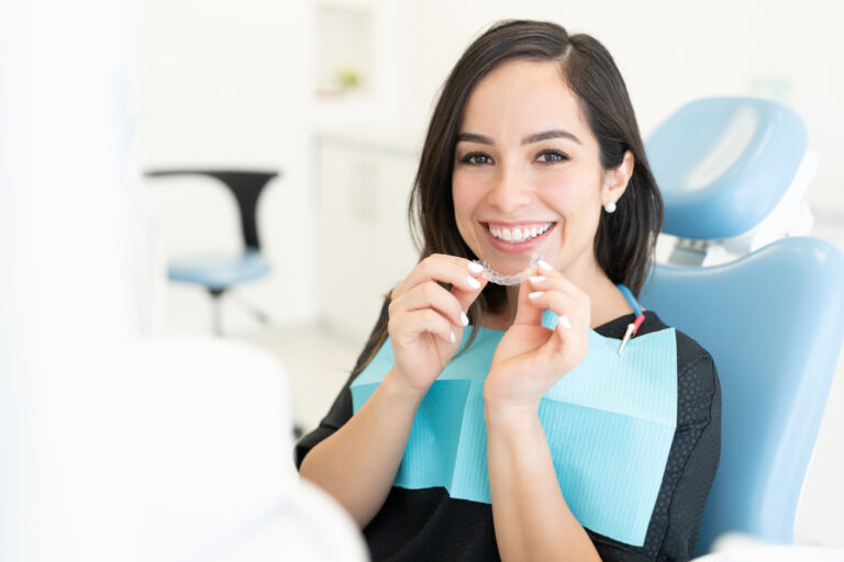 Smiling beautiful woman holding invisible orthodontic retainer