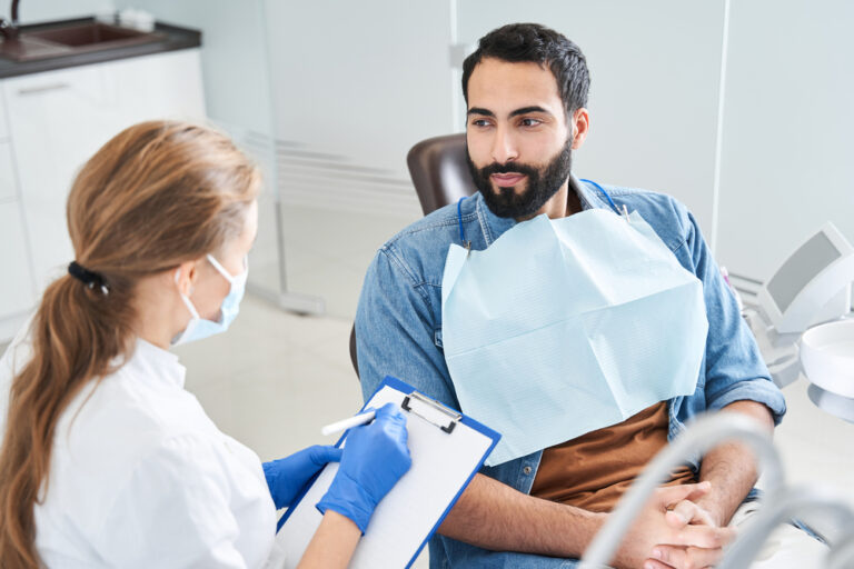 Female dentist in dental office talking with male patient