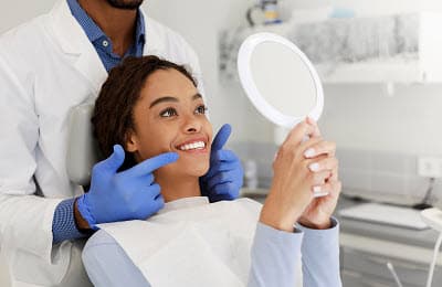 Lady checking her beautiful smile in mirror after treatment
